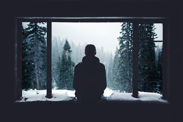 muž pozorující zimu z okna